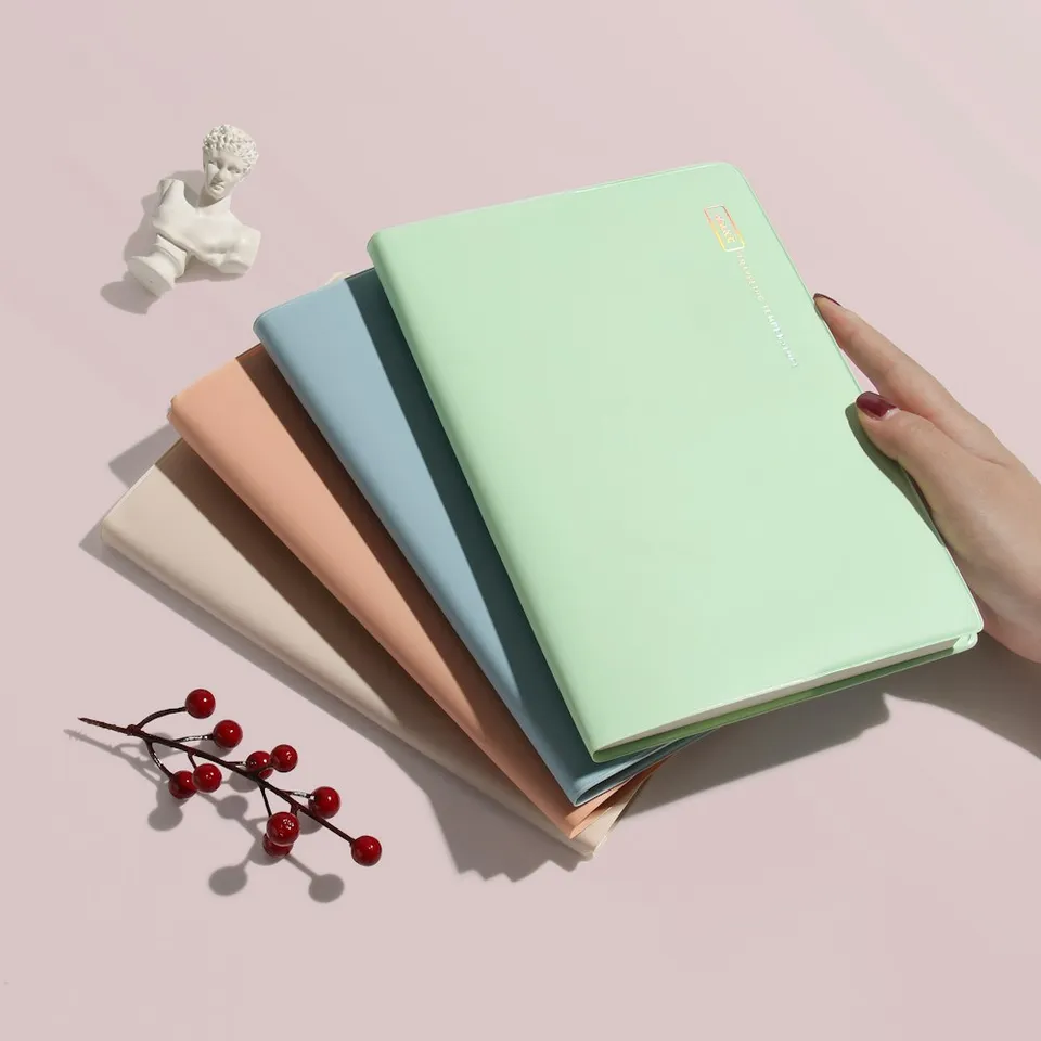 Cuadernos apilados en tonos pastel sobre una mesa